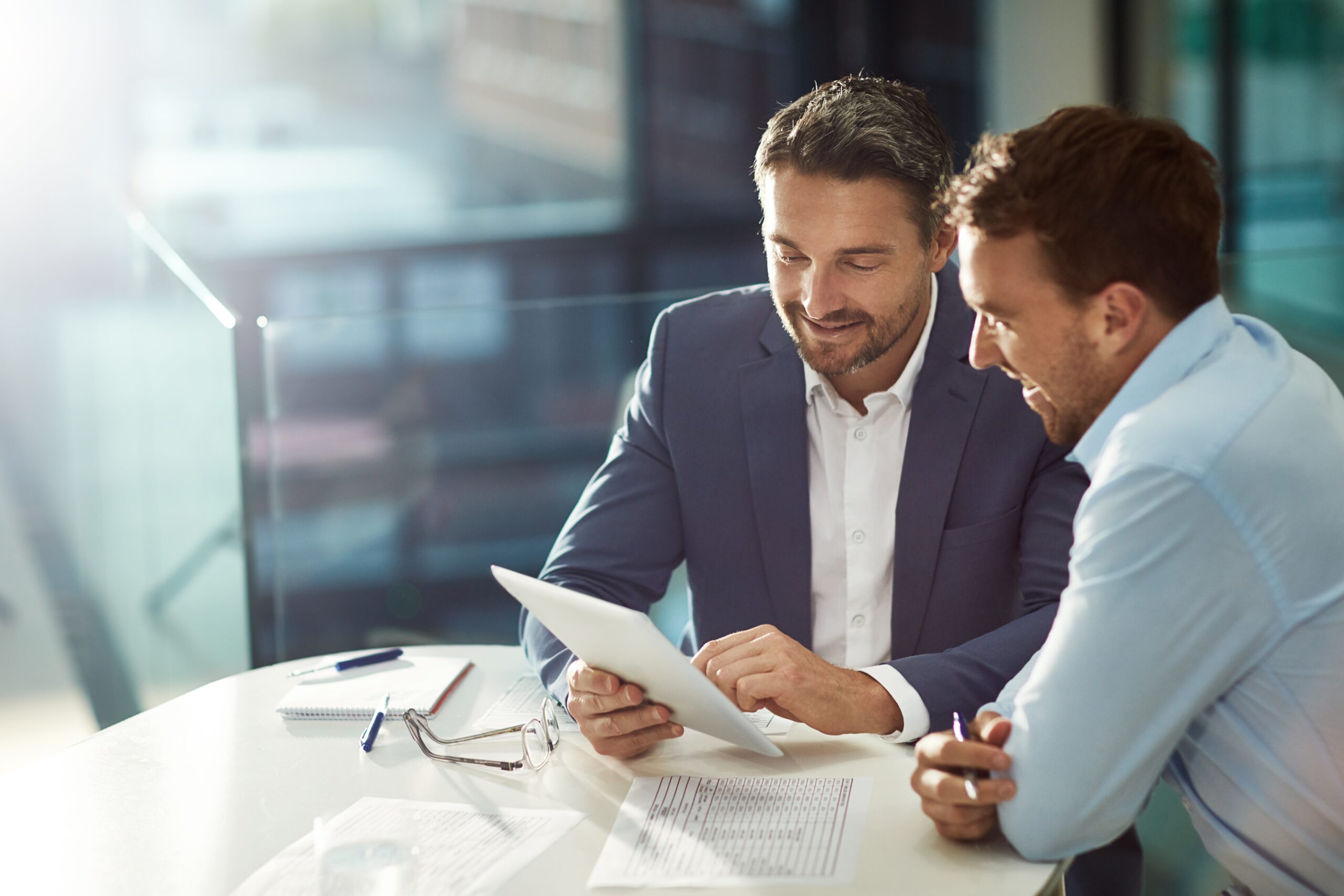 2 business men smiling looking at a document